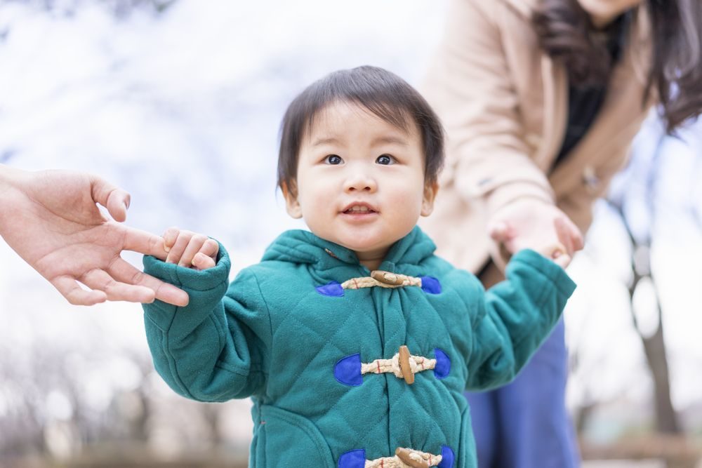 両親と手をつなぐ幼い男の子の写真