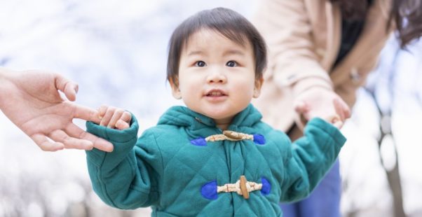 両親と手をつなぐ幼い男の子の写真