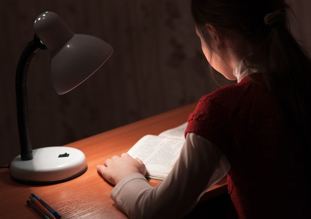 薄暗い部屋で本を読む子どもの写真