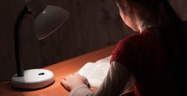 薄暗い部屋で本を読む子どもの写真