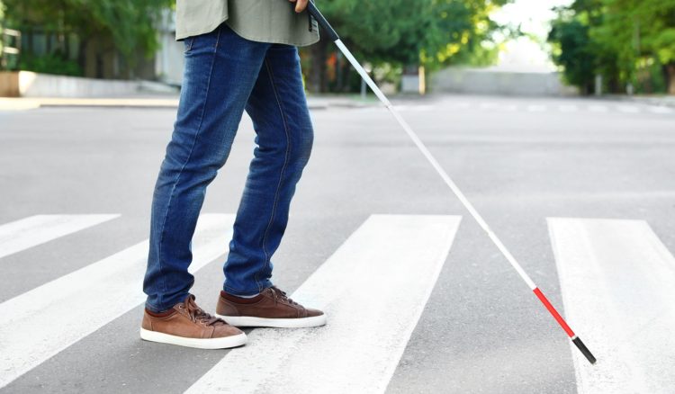 白杖をもって横断歩道を渡る視力障がいの男性