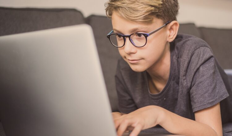 パソコンを使って画面を見るメガネをかけた男の子