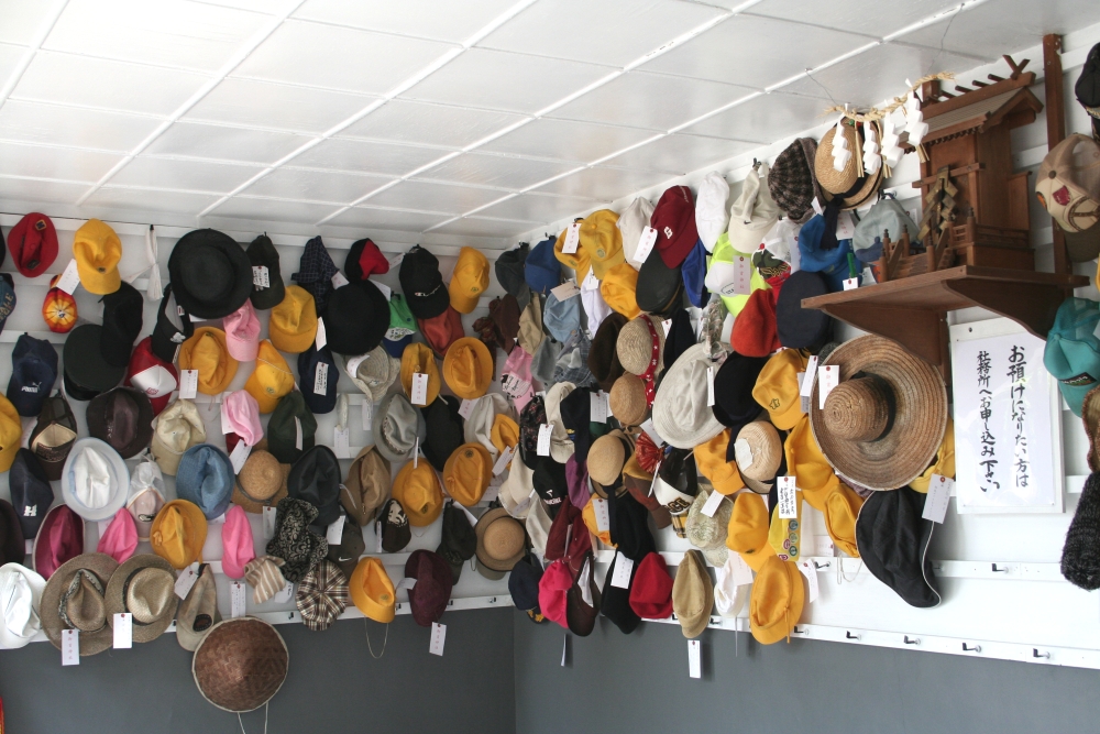 帽子やスカーフなどの首から上の部分に身に着ける着装品が奉納されている写真