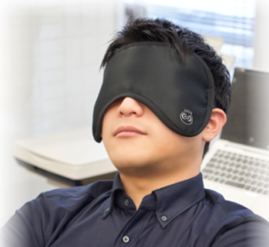 睡眠の質を高めるといわれている血行促進アイマスクを着用して休息をとる男性