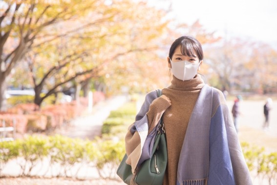 花粉対策をして秋の公園を歩く女性