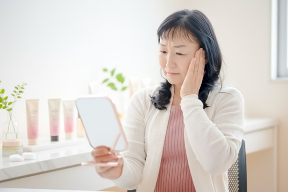 自分で鏡を見て悩んでいる女性